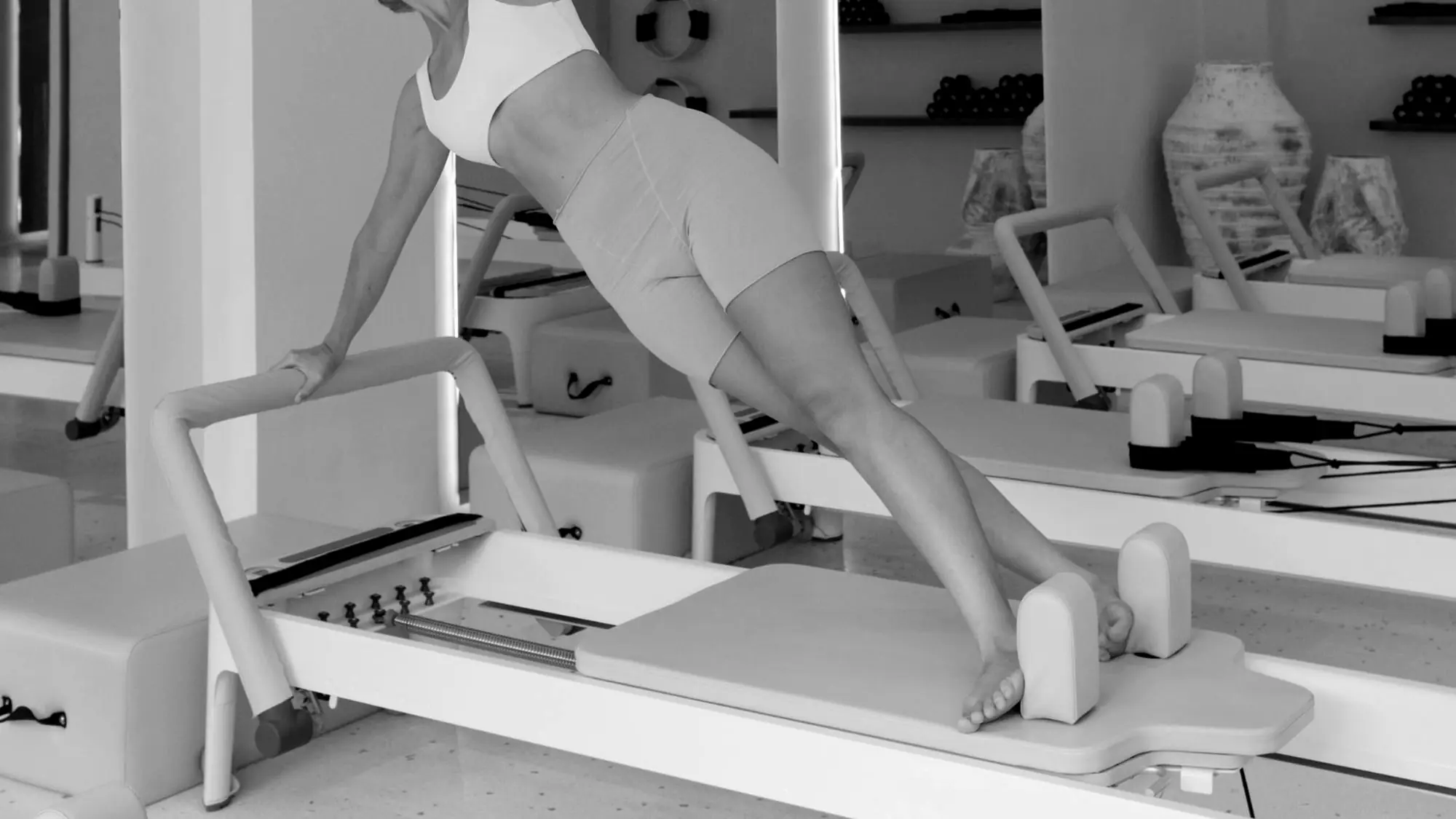 Woman holding a plank on a carriage machine in a bright studio