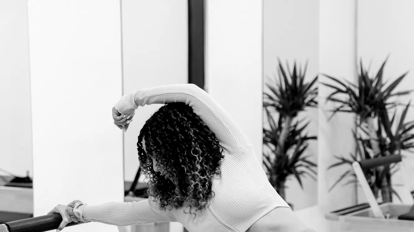 Woman stretching sideways over a Pilates reformer
