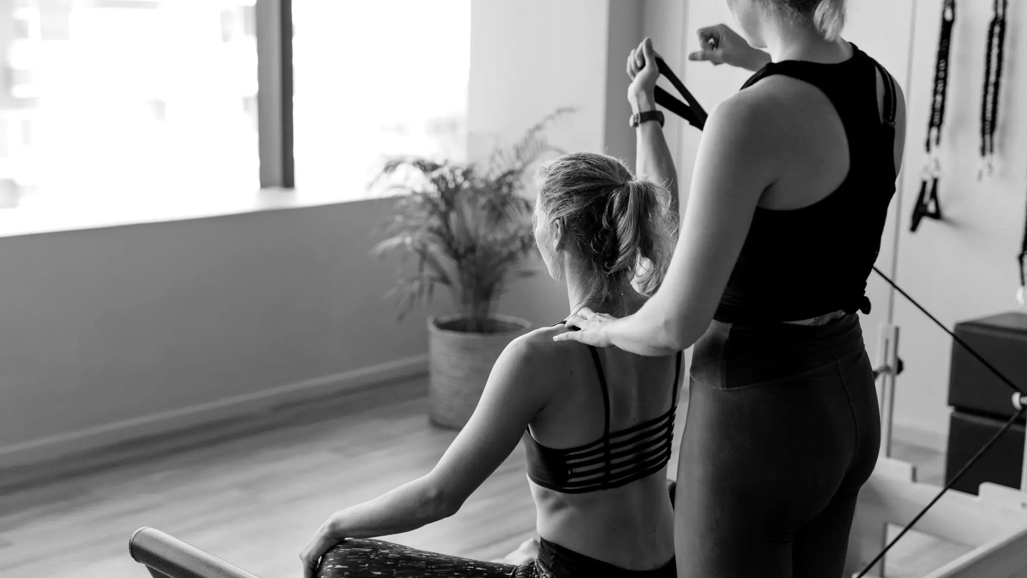 Instructor adjusting a student's shoulders during a private Pilates session