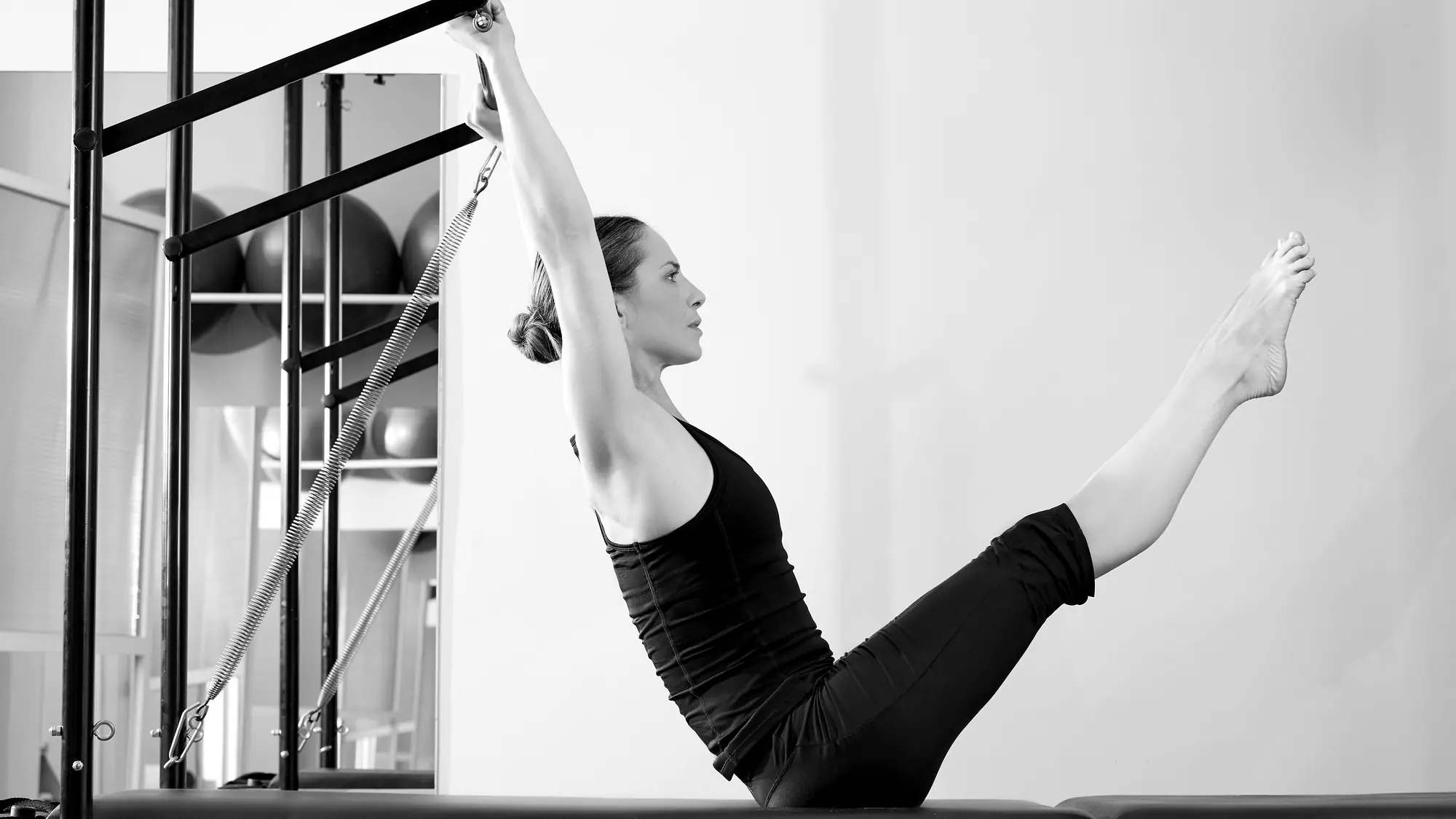 Woman balancing in a V-sit while holding a bar overhead