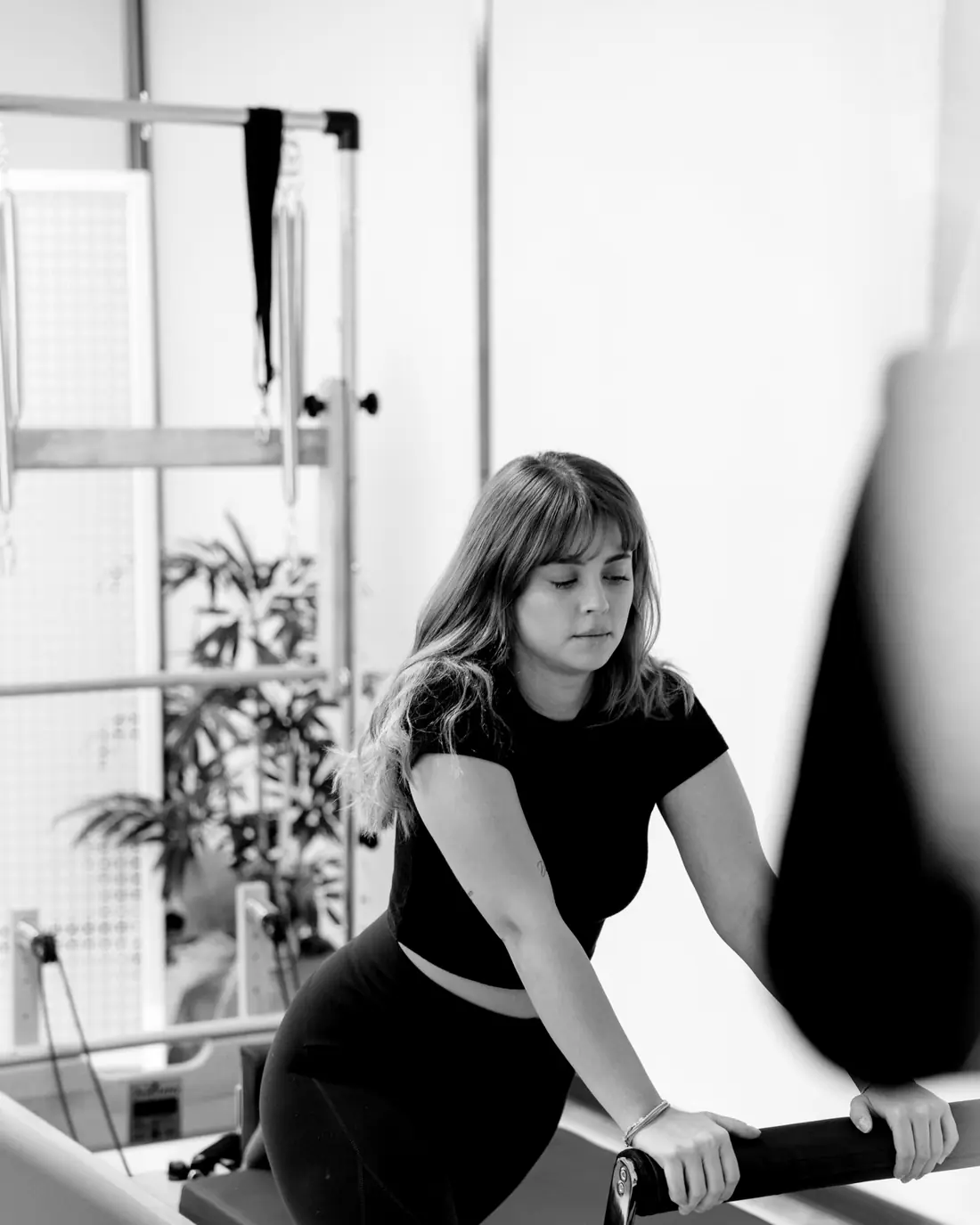 Woman working on a Pilates reformer carriage with a straight-bar handle